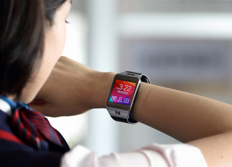 A member of Japan Airlines Co. ground staff talks on a Samsung Galaxy Gear 2 Lite smartwatch, manufa...