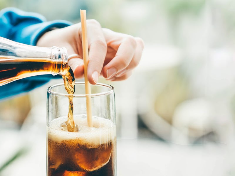 A woman pours ice-cold cola into glasses.