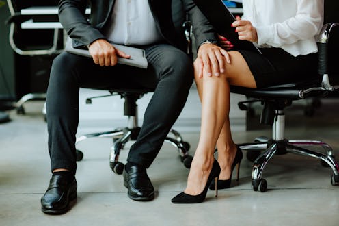 Business man in black and white look is touching woman's leg. People are sitting in leather black ch...