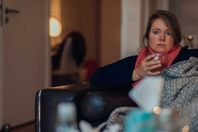 Ill woman drinking warm tea at home.
