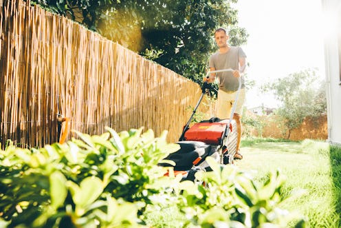 Man using a lawn mower in his back yard.