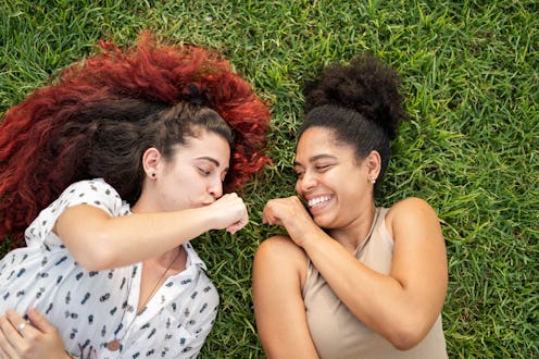 Top view of two female friends having fun lying down in a park
