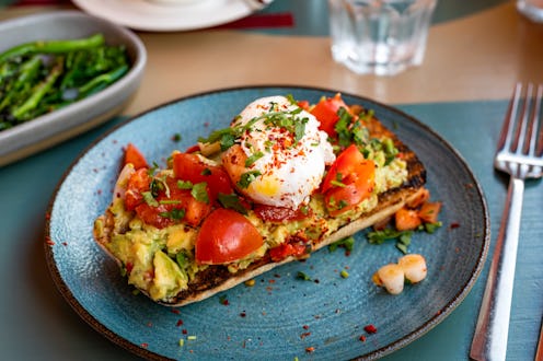 Healthy breakfast with Smashed Avocado and Tomatoes and Poached Egg on toasted ciabatta served in ca...