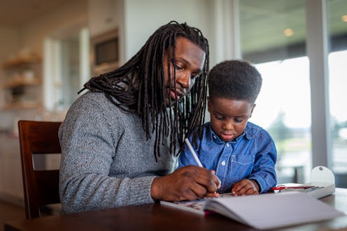 Loving and involved father sits next to his adorable preschool age son of African American ethnicity...