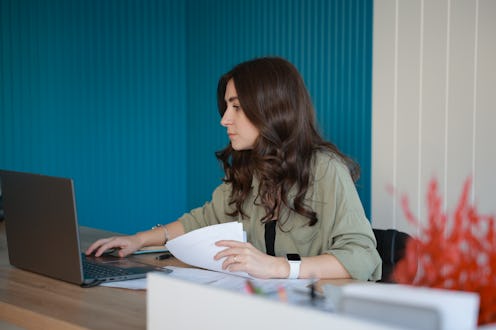 Young happy and successful businesswoman in glasses working with documents inside office, Hispanic w...