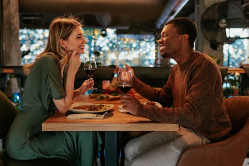 A happy young couple is on a Valentines day dinner date in a fancy restaurant.