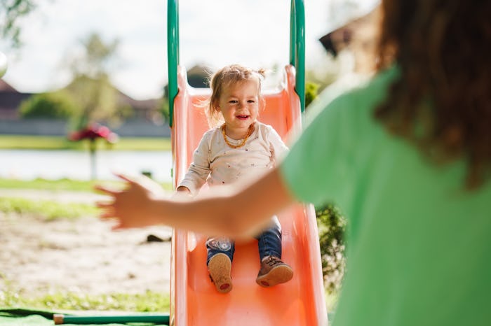 Happy girl and her sister playing at playground during sunny day