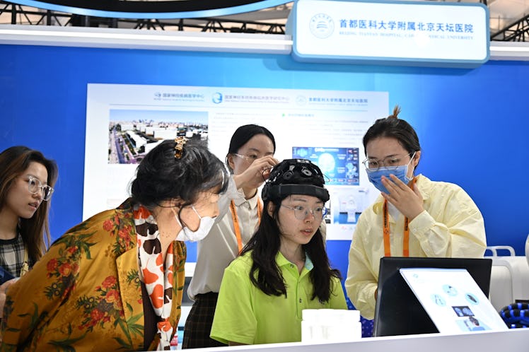 A visitor experiences domestic brain-computer interface system at the booth of Beijing Tiantan Hospi...