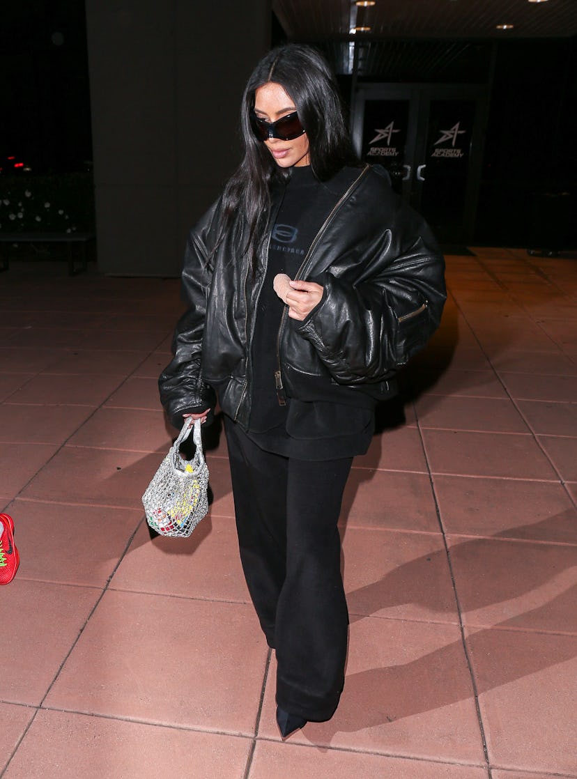 Kim Kardashian wears an all-black ensemble with a sparkly net bag on February 09, 2024.