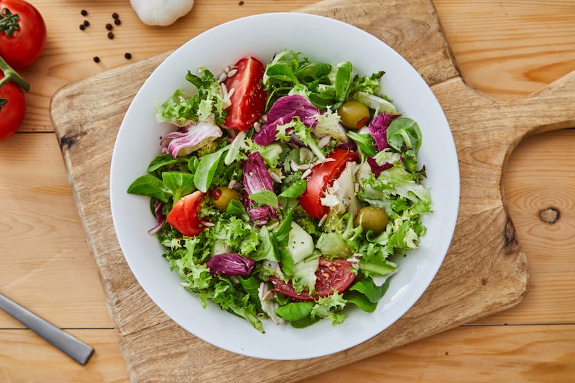 Delicious homemade gourmet healthy green salad bowl, with green salad lettuce, olive oil, garlic and...