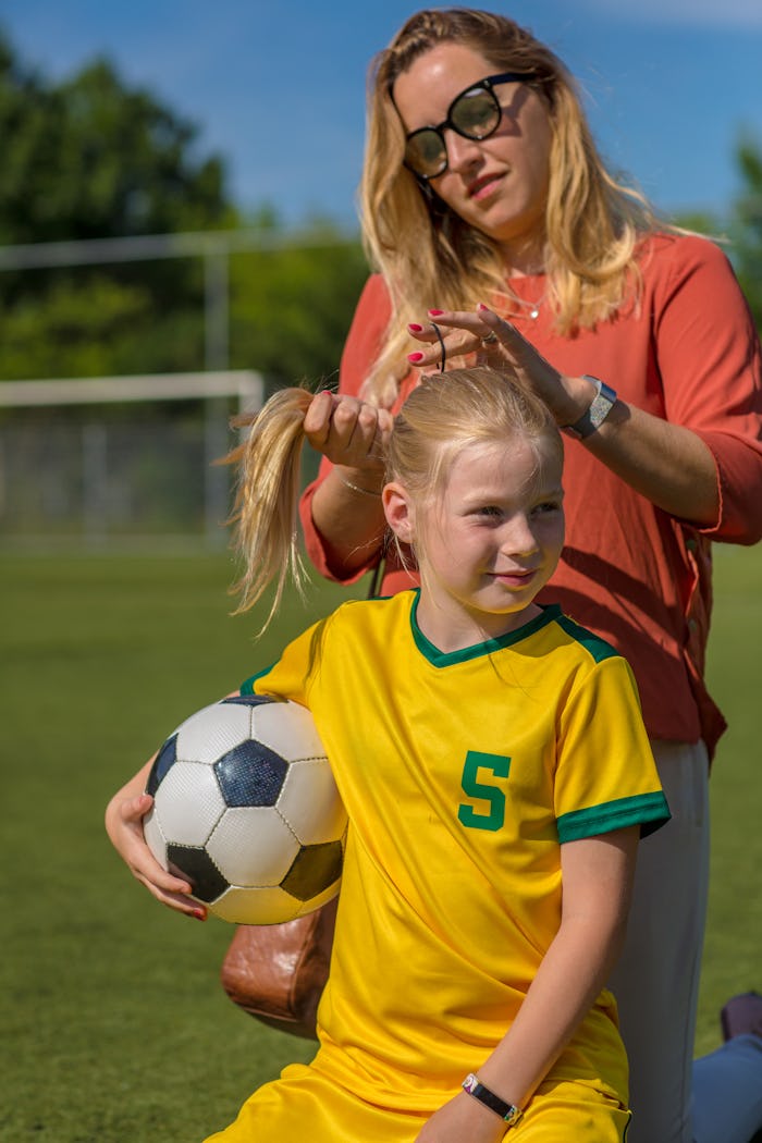 Soccer Mom preparing her blond daughter for football training