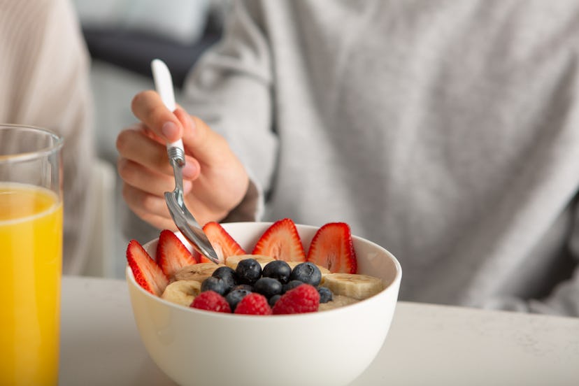 Young male adult having cereal in kitchen.