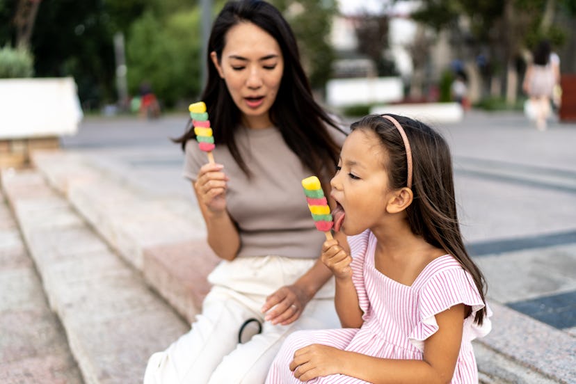 Happy mother and little daughter eating ice cream in summer day