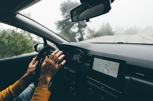 Man driving car on road in autumn forest.