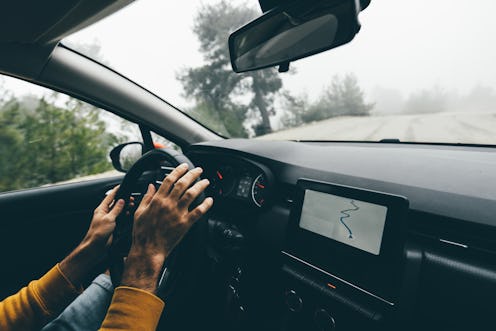 Man driving car on road in autumn forest.