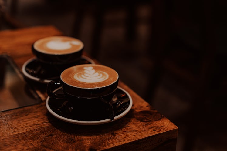 Two coffee cups with latte art on the wooden table