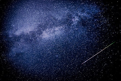 A meteor shoots across the night sky sky leaving a trail of light across the milky way