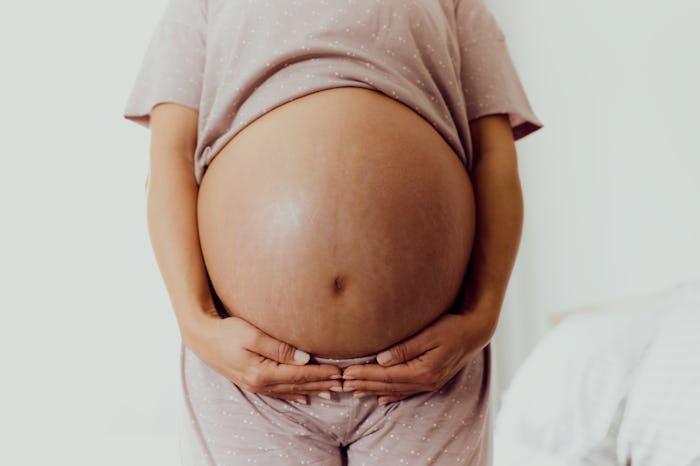 Close up of unrecognizable pregnant woman's stomach with stretch marks. Copy space.