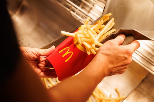 02 December 2021, Bavaria, Munich: An employee fills a bag with French fries at a branch of the McDo...