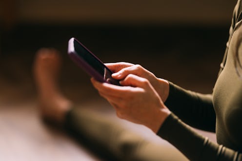 Close-up of female hands using a smartphone, likely managing a fitness app during a workout
