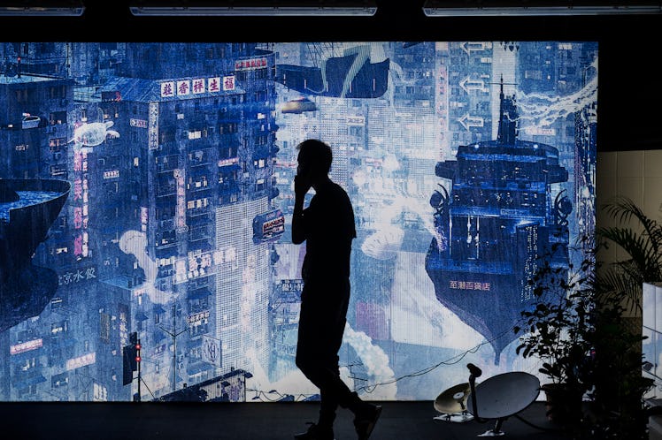 HONG KONG, CHINA - 2020/10/15: A man walks past a futuristic urban city landscape as part of the Cyb...