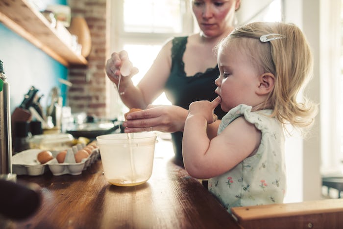 Mother and toddler daughter in kitchen preparing food.