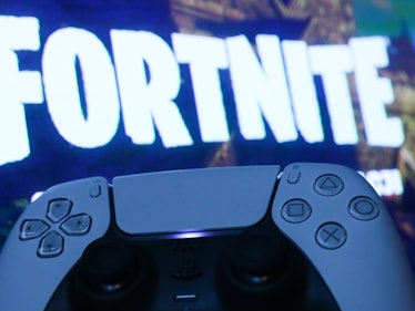 PlayStation DualSense controller and Fortnite on PlayStation Store displayed on a tv screen are seen...