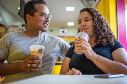 Portrait of a young multiracial couple, having milkshake together at an ice cream shop and Feeling h...