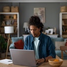 Young African American freelancer typing an e-mail on a computer at home office.