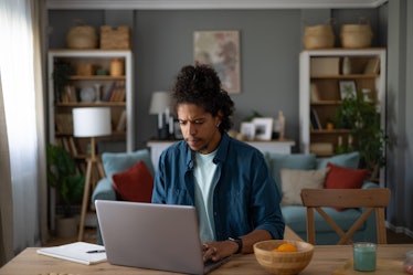 Young African American freelancer typing an e-mail on a computer at home office.