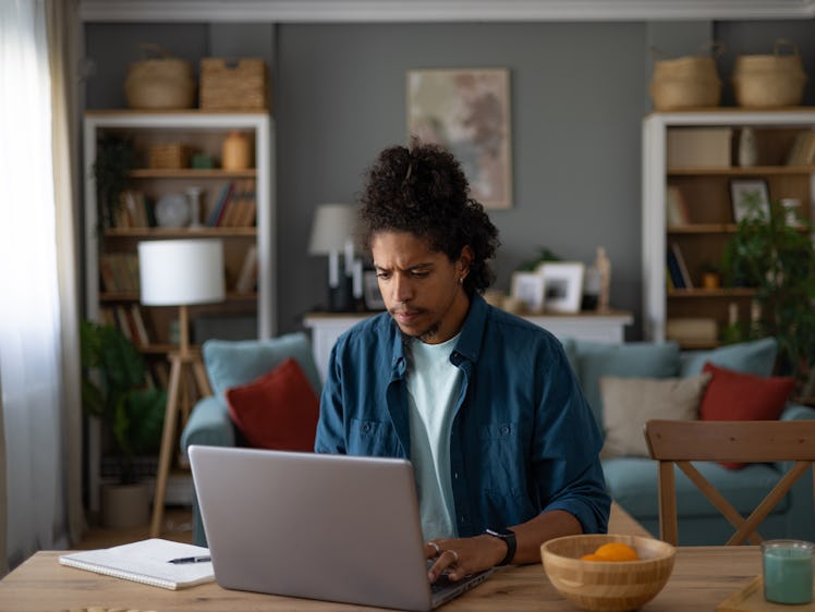 Young African American freelancer typing an e-mail on a computer at home office.