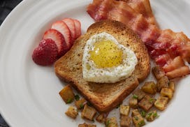 Romantic Breakfast in Bed with Heart Shaped Fried Egg, Whole Grain Toast, Hash Browns and Bacon