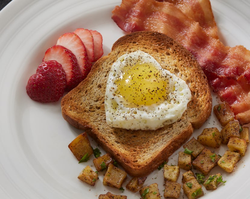 Romantic Breakfast in Bed with Heart Shaped Fried Egg, Whole Grain Toast, Hash Browns and Bacon
