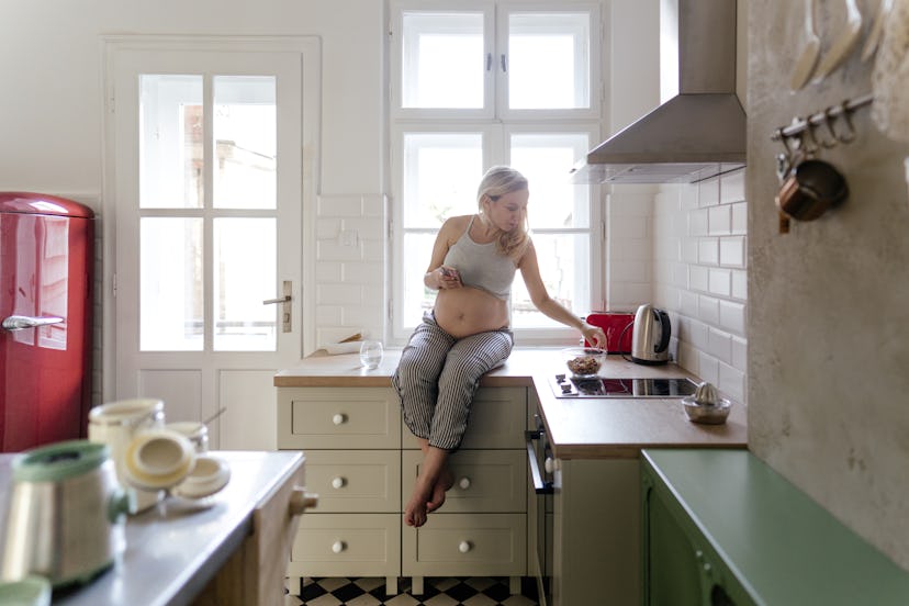 Photo of a pregnant woman having a snack in her kitchen, in a story on myths about gestational diabe...