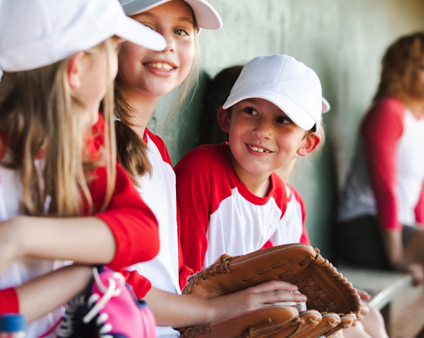 A dugout is occupied by six children who are in elementary school, and they're dressed in baseball t...