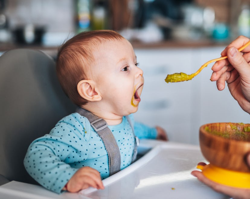 Father spoon feeding his infant son at home. instagram captions for pictures of your baby's first so...