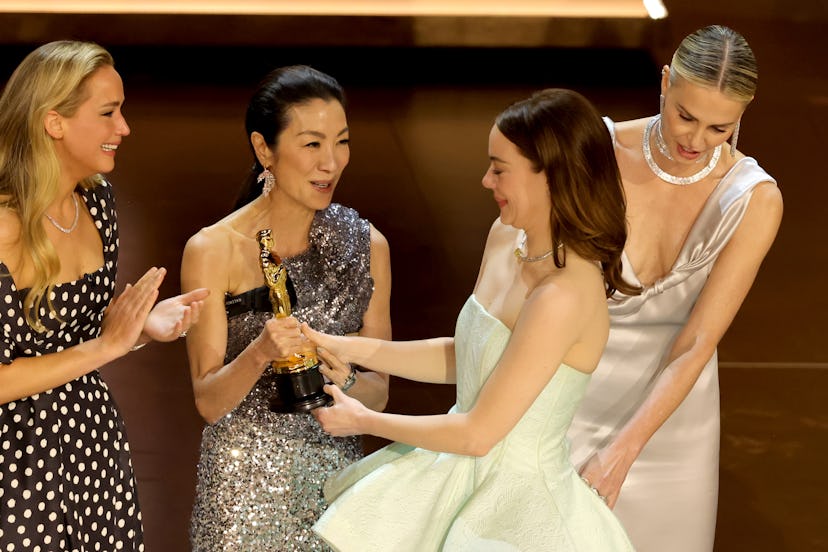 Emma Stone accepts her Oscar from Michelle Yeoh and Jennifer Lawrence.