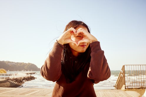 She peeks into the heart with her fingers and looks at the camera.