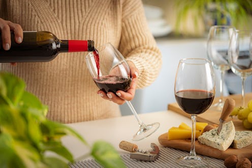Close up of a woman pouring red wine into a glass on party table