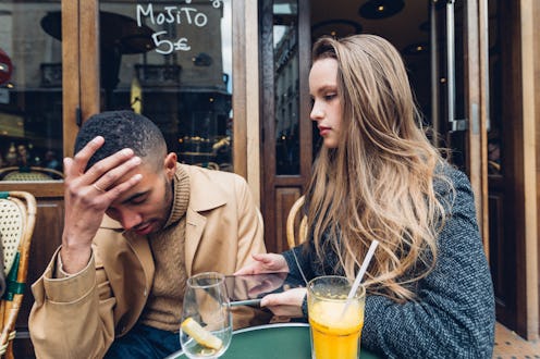 A concerned pair discussing their financial situation at an outdoor cafe