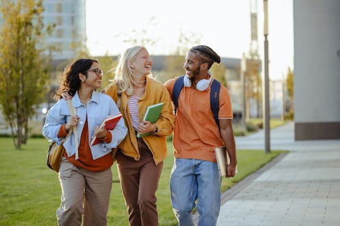 Student friends walking in university campus, embracing and chatting during break