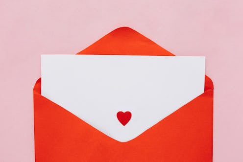 Blank Valentine card with red envelope and paper heart on pink backgrount. Flat lay. Top view