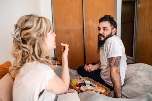 Couple talking and having breakfast in bed at home