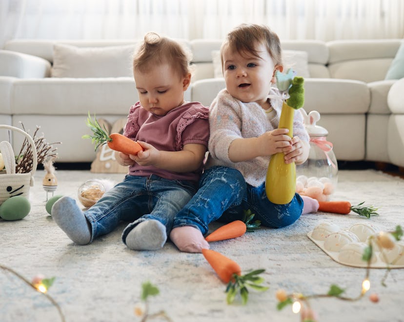 Playful twin caucasian sisters decorating for Easter. They are in the domestic room, collecting eggs...
