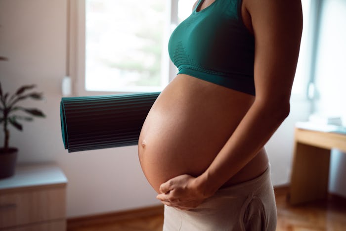 Pregnant woman getting ready to exercise at home, in a story about skin tags during pregnancy.