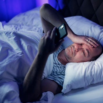 Middle aged balding man lying bed and using a mobile phone. Sleeping disorder and mobile addiction.
...