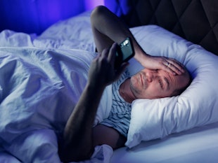 Middle aged balding man lying bed and using a mobile phone. Sleeping disorder and mobile addiction.
...