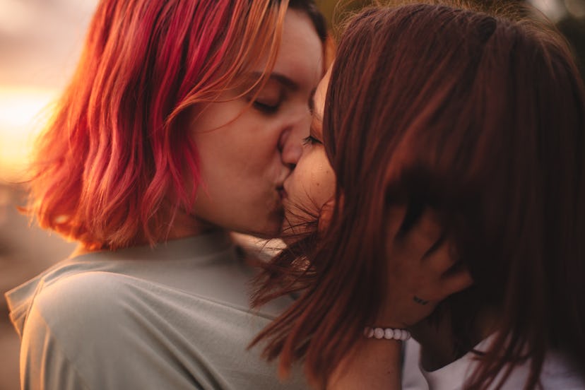 Lesbian couple kissing at sunset during summer
