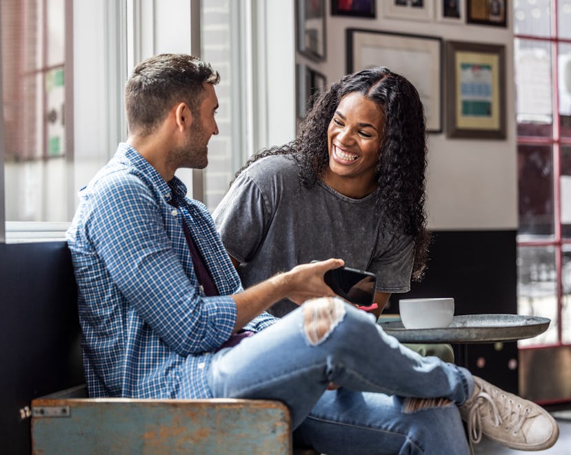 Young couple using smartphones and laughing in coffeeshop