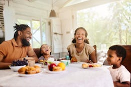 Cheerful African American family having fun during a meal in dining room.